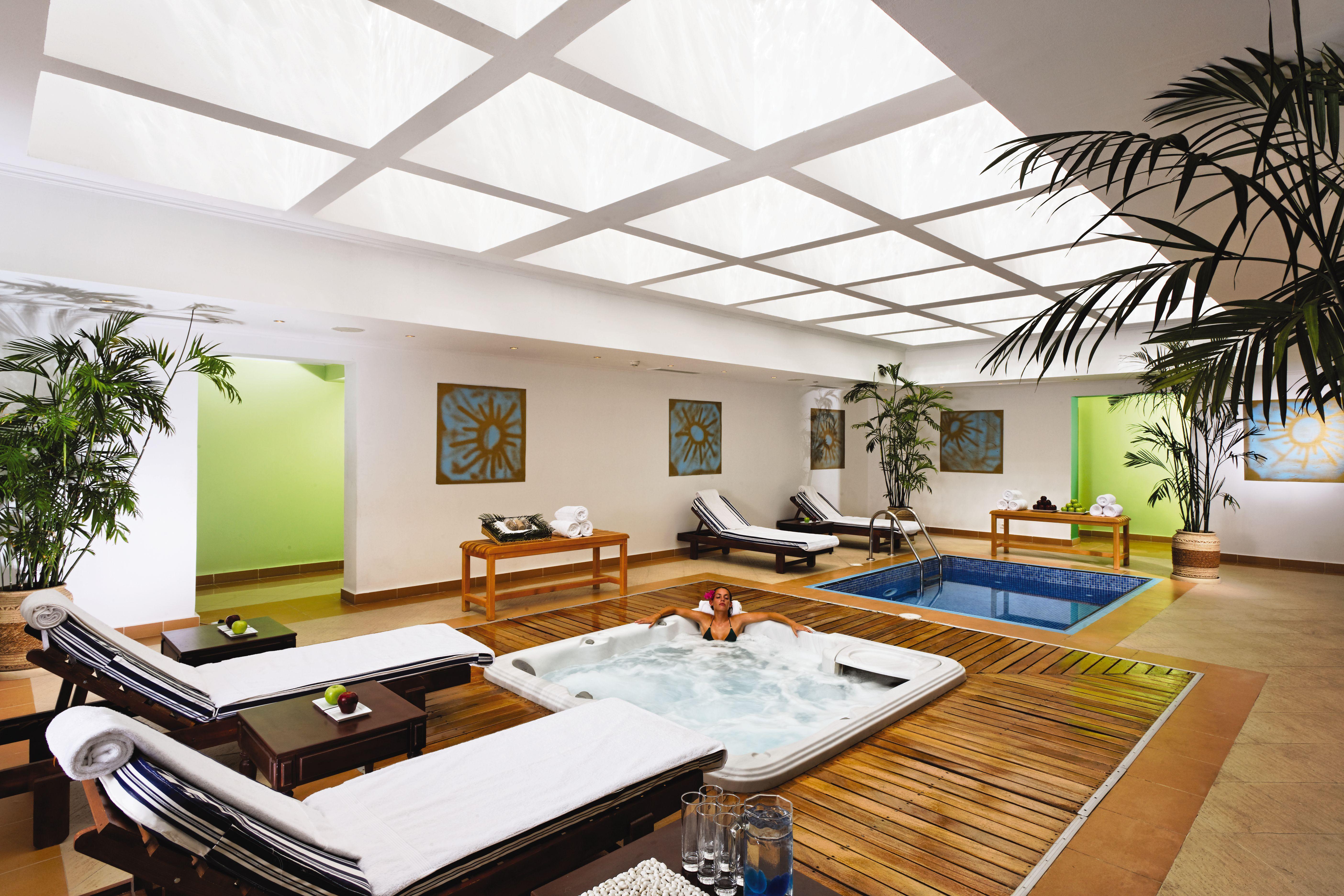 Movenpick Taba Resort & Spa Faciliteter billede The photo shows an indoor spa or relaxation area. It features a small pool and a hot tub, surrounded by wooden decking. There are lounge chairs, likely for relaxation, placed around the space. The walls are painted in soft colors, and there are decor