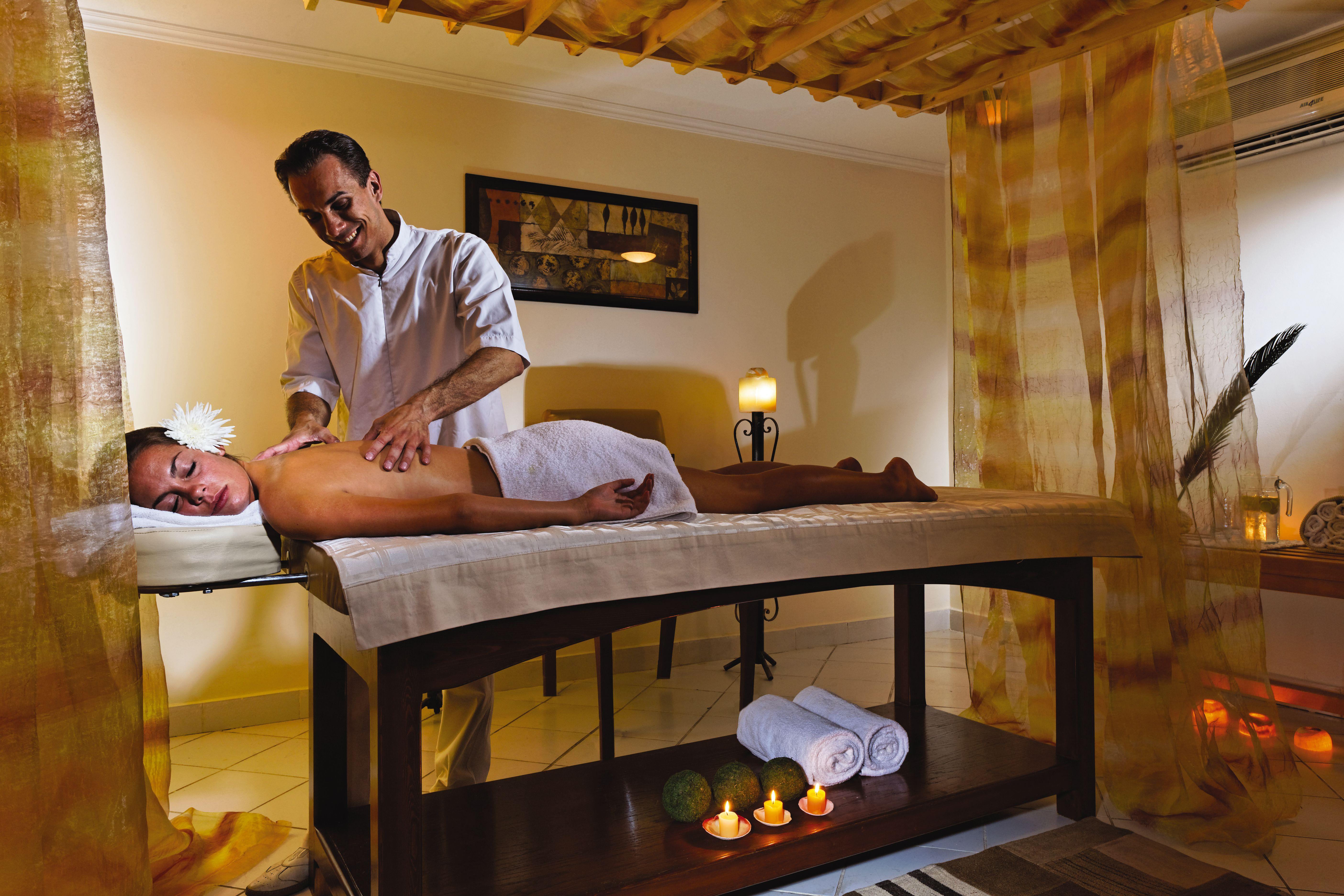 Movenpick Taba Resort & Spa Eksteriør billede The photo shows a tranquil spa setting where a massage is taking place. A person lies on a massage table, covered with a white towel, while a therapist administers a massage. The room is softly lit and decorated with calming colors. There are candles