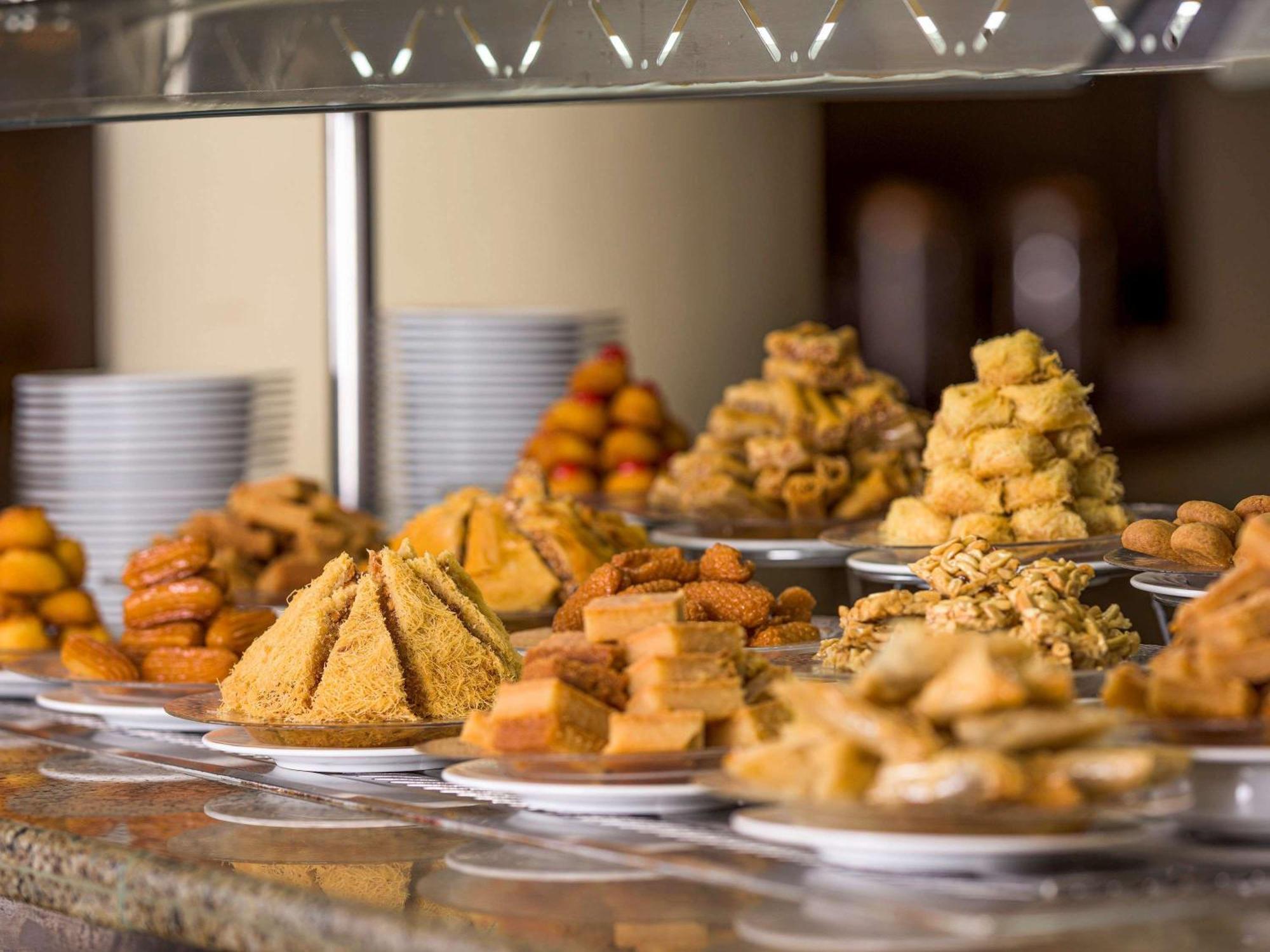 Movenpick Taba Resort & Spa Eksteriør billede The photo showcases a variety of desserts displayed on a table. There are several types of sweet treats, including pastries and confections. Some are arranged in pyramid shapes, while others are in neat piles or on small plates. The desserts appear t