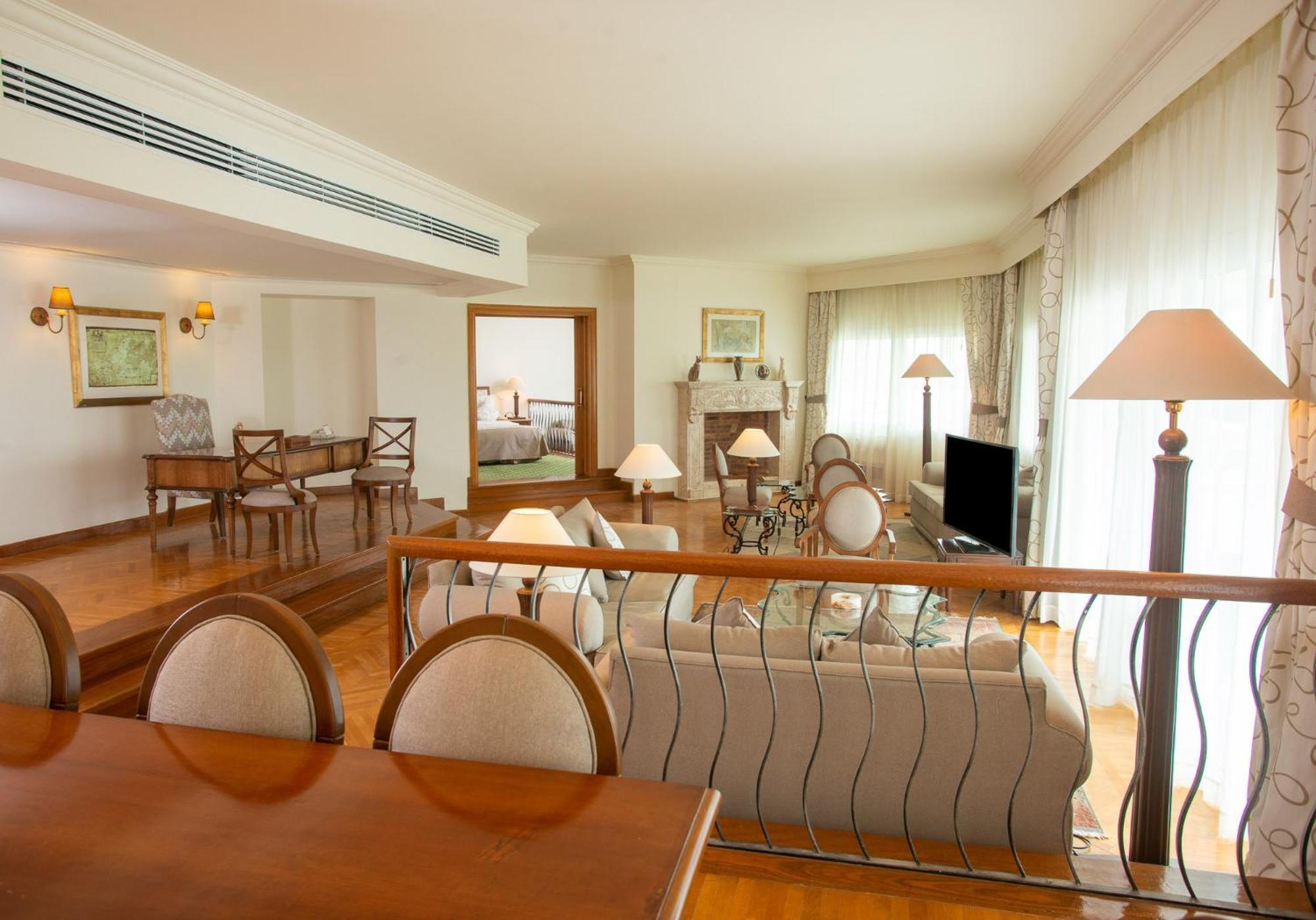 Movenpick Taba Resort & Spa Eksteriør billede The photo showcases a spacious and elegantly designed living area. In the foreground, there is a dining table with chairs, providing a formal seating arrangement. The background features a lounge area with a comfortable sofa, several side lamps, and 